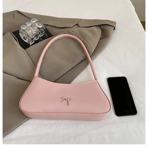 Close-up of pink baguette bag with silver bow detail and smartphone for size reference