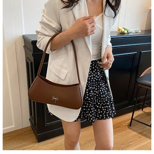 Braune Baguette-Schultertasche mit silberner Schleife kombiniert mit weißem Blazer
