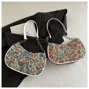 Détail de sacs hobo en jacquard floral avec anses en cuir blanc et nœuds argentés
