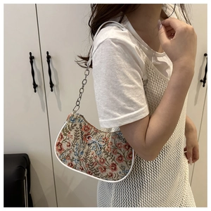 Détail d'un sac en brocart floral avec nœud argenté et bandoulière en chaîne