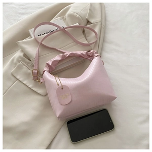 Detail of light pink pleated handbag with ruffled handle and fashion bag tag over a blazer