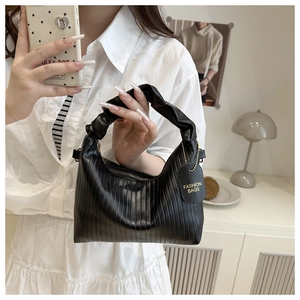 Detail of black pleated hobo bag with moon shape design and branded fashion tag