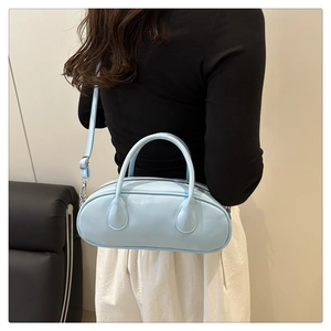 Detail of light blue faux leather boston bag with sleek handles and adjustable shoulder strap