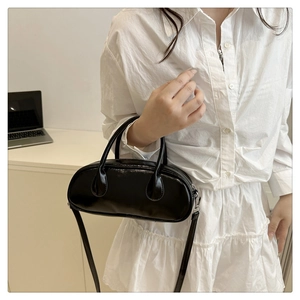 Detail of glossy black patent leather shoulder bag with sleek handles and strap
