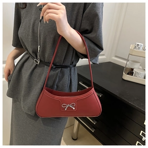 Detailed view of burgundy leather shoulder bag featuring a silver bow accent