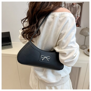 Detail view of a black hobo bag with a silver bow buckle worn on the shoulder