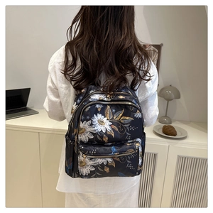 Fashionable black backpack with daisy floral print and gold zippers on model back