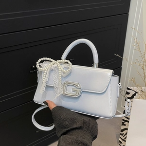 Detail of light blue patent leather handbag with rhinestone G buckle and lace bow