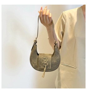 Détail du sac demi-lune gris-vert avec texture vintage et logo en métal doré