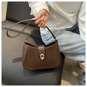 Detail of a brown half-moon bag featuring a distinctive gold ring buckle and matte leather