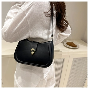 Rear view of a model wearing a black semi-circular shoulder bag with golden buckle detail
