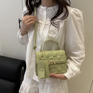 Detail view of avocado green crossbody bag with checkered texture and pearl buckle