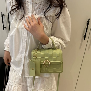 Detail of mini green crossbody bag with pearl gold buckle and quilted texture