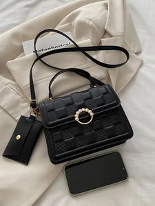 Close-up of black textured leather mini bag with pearl buckle and matching coin purse