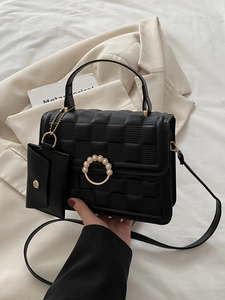 Detail of black quilted leather crossbody bag with gold pearl buckle and mini coin pouch