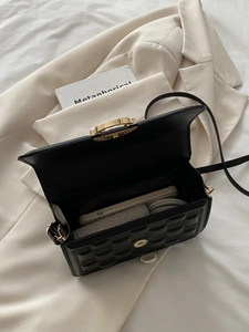 Detail view of the spacious interior of a black quilted chain bag with gold hardware