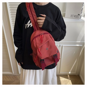 Close-up of a versatile red waterproof nylon chest bag worn by a model in a casual setting