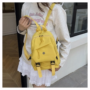 Detail view of yellow nylon backpack with front flap pocket and dual buckle fasteners