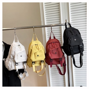 Detail of multi-pocket nylon backpacks in white, yellow, red and black with fashion straps