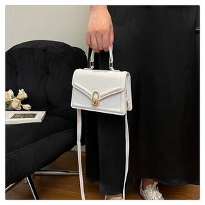 Detail of white PU leather crossbody bag with golden oval clasp and fixed top handle