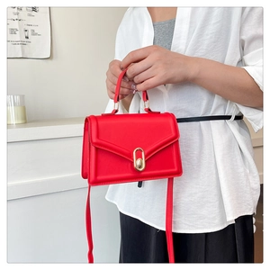 Detail of red crossbody bag with golden oval twist lock and sleek leather texture