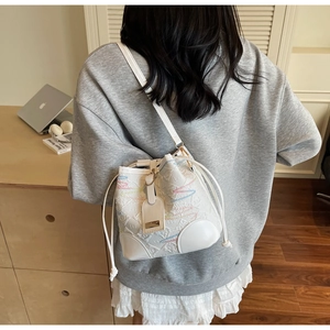 Detail of white bucket bag featuring colorful wavy stitching and drawstring closure