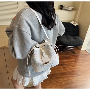 Detail of white bucket bag featuring colorful wave embroidery and leather shoulder strap