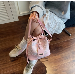 Detail of pink bucket bag with embossed texture and rainbow stitching on crossbody strap
