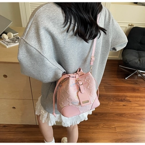 Detail of pink drawstring bucket bag featuring embossed patterns and fine embroidery