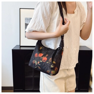 Detail of crossbody bag with orange persimmon and bamboo leaf patterns on black fabric