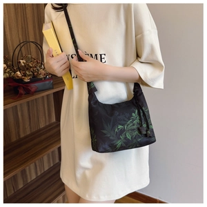 Close-up of black nylon crossbody bag with green leaf pattern in a casual lifestyle setting