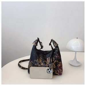 Detail of vintage floral canvas crossbody bag next to a smartphone for size reference