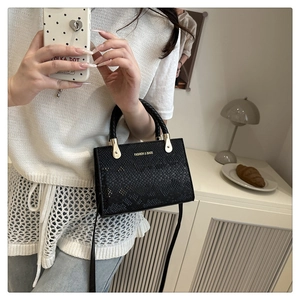 Detail of vintage black snake-embossed small square bag with woven handle and gold accents
