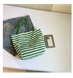 Détail d'un sac cabas en toile à rayures vertes et blanches avec logo en cuir et anses