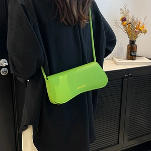 Minimalist bright green lychee textured crossbody bag shown on a model in a modern interior