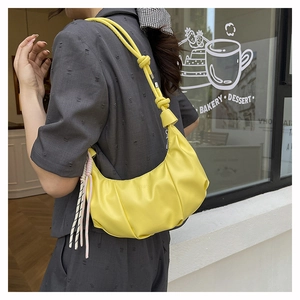 Detail of a bright yellow crescent bag with pleated PU leather and knotted shoulder strap