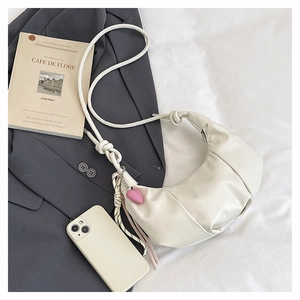 Détail du sac beige avec bandoulière à nœuds épais et breloque en cœur rose