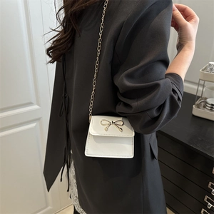 Chic white mini saddle bag with golden bow clasp and chain strap for stylish crossbody wear