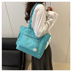 Detail of bright blue nylon shoulder bag with zipper pocket and good luck patch