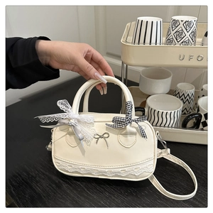 Detailed close-up of cream Boston bag featuring lace edges and ribbon bow accents