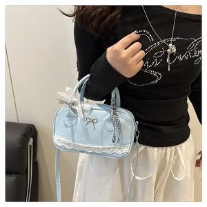 Detail of light blue ballet-style Boston bag with white lace trim and silver bow buckle