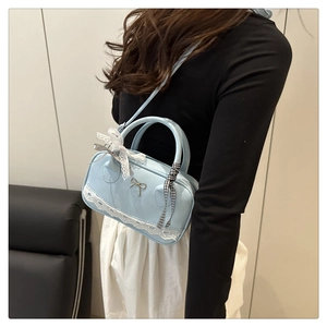 Dettaglio borsa a tracolla azzurra con bordo in pizzo e ciondolo a fiocco decorativo