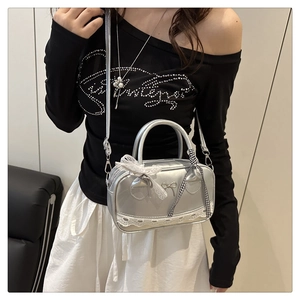 Detail of silver Boston bag with lace trim, metallic bow, and checkered ribbon accents