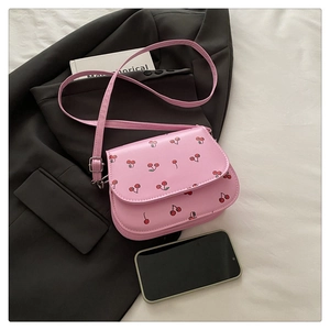 Detailed view of pink crossbody bag featuring red cherry prints and silver metal buckle