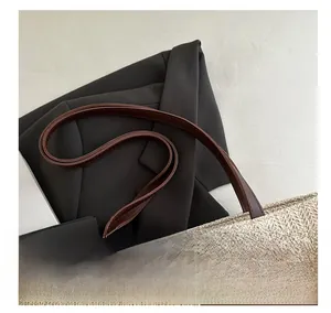 Detail shot of woven straw tote bag featuring premium brown leather handles and tight texture