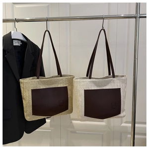 Detail of woven straw tote bags with brown leather bear pockets and sturdy dual handles