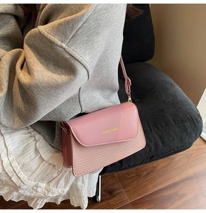 Detail of pink crossbody bag showing leather and woven texture mix with gold lettering