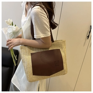 Detail of woven straw tote bag with brown leather bear pocket and long shoulder straps