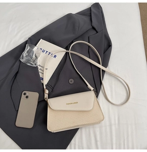 Detail of cream white leather and woven fabric shoulder bag with gold lettering