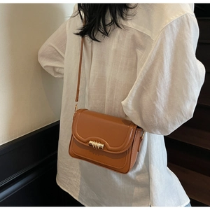Detailed view of caramel brown faux leather crossbody bag with gold-tone hardware and buckle